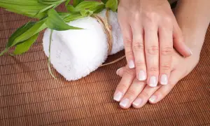 Delikatne dłonie z francuskim manicure, biały ręcznik i zielone liście bambusa. Czy to jest manicure japoński?