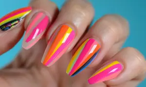 Kolorowy, neonowy manicure na lato w paski. Odcienie różu, pomarańczu, żółci i błękitu tworzą energetyczną kompozycję.