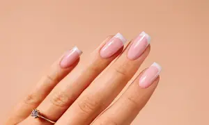Dłoń z paznokciami w stylu french ze wzorkiem. Delikatny róż i biel tworzą klasyczny, elegancki manicure.