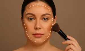 Kobieta nakłada bronzer pędzlem, tworząc kontur twarzy. Pokazano, jak wyszczuplić twarz za pomocą makijażu.