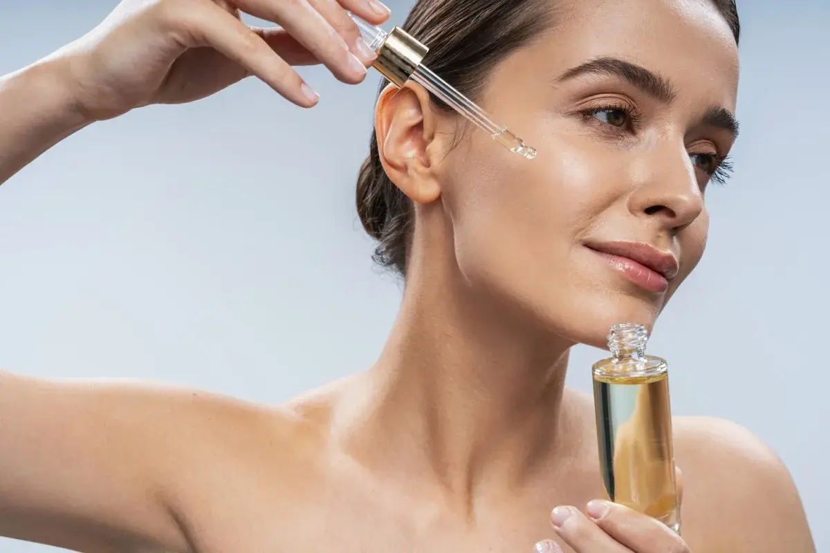 Kobieta aplikuje serum na twarz. Zastanawiasz się, jaki peeling do twarzy wybrać? Ten olejek może być odpowiedzią.
