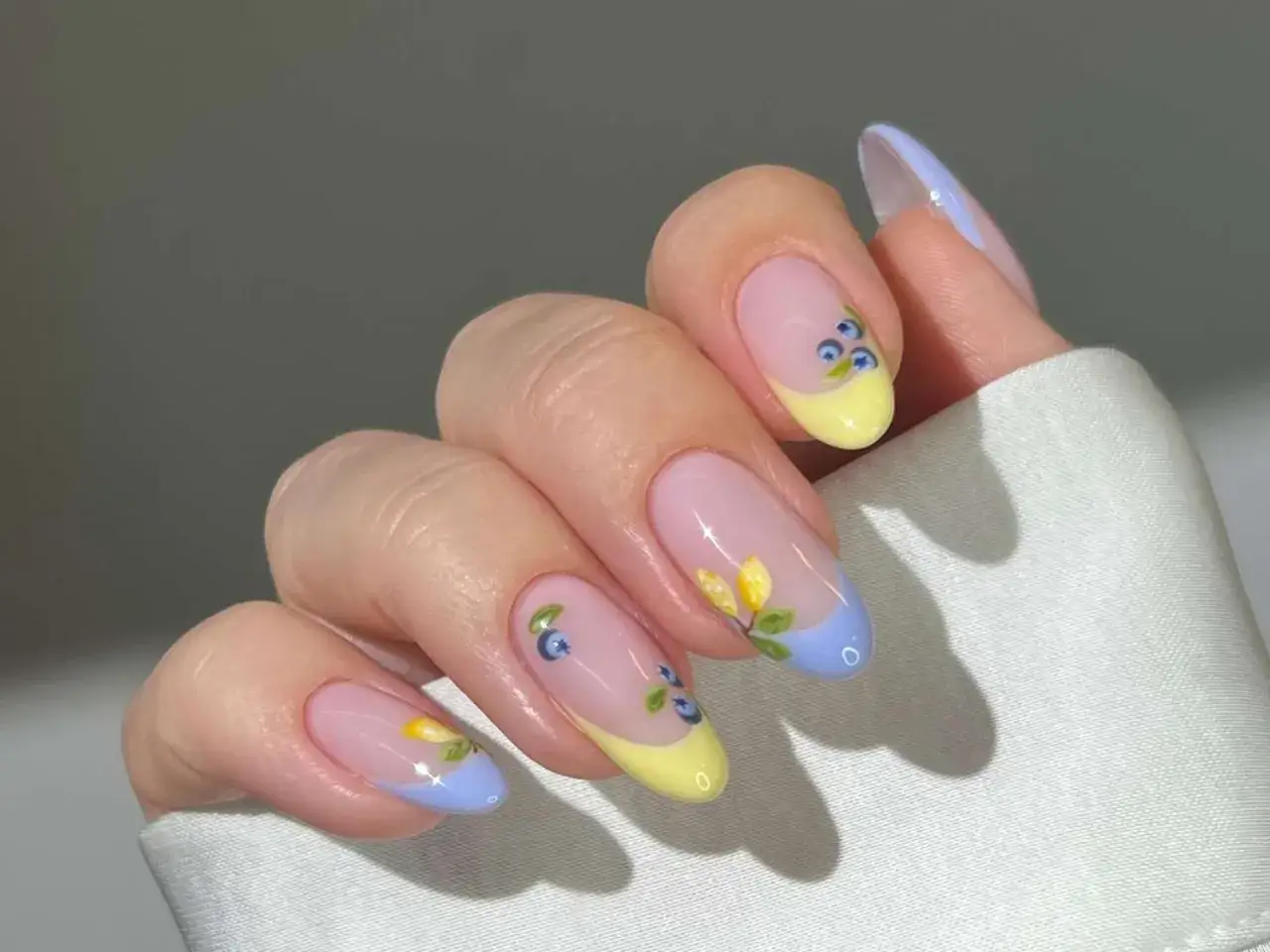 Delikatny french manicure ze wzorkiem jagód i kwiatów. Paznokcie w pastelowych kolorach, z subtelnym motywem natury.
