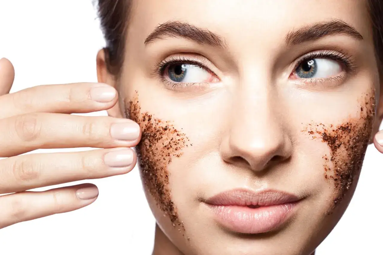 Kobieta aplikuje na twarz peeling kawowy, który jest doskonałym wyborem, jeśli zastanawiasz się, jaki peeling do twarzy wybrać dla promiennej cery.